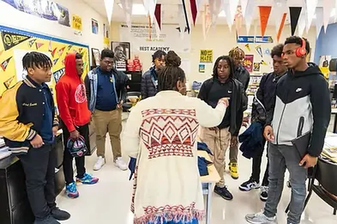 A facilitator teaching a Financial Foundations™ lesson to a circle of high-school students in a classroom
