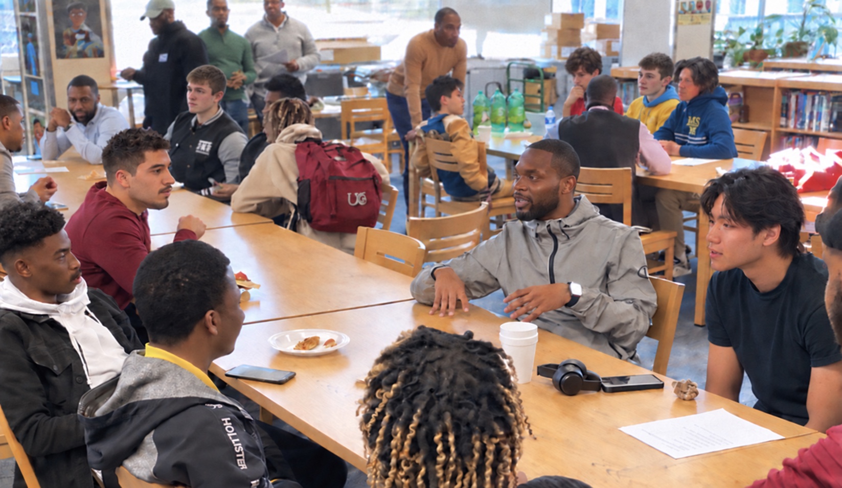 A facilitator leading a Financial Foundations™ session with students at tables in a school cafeteria