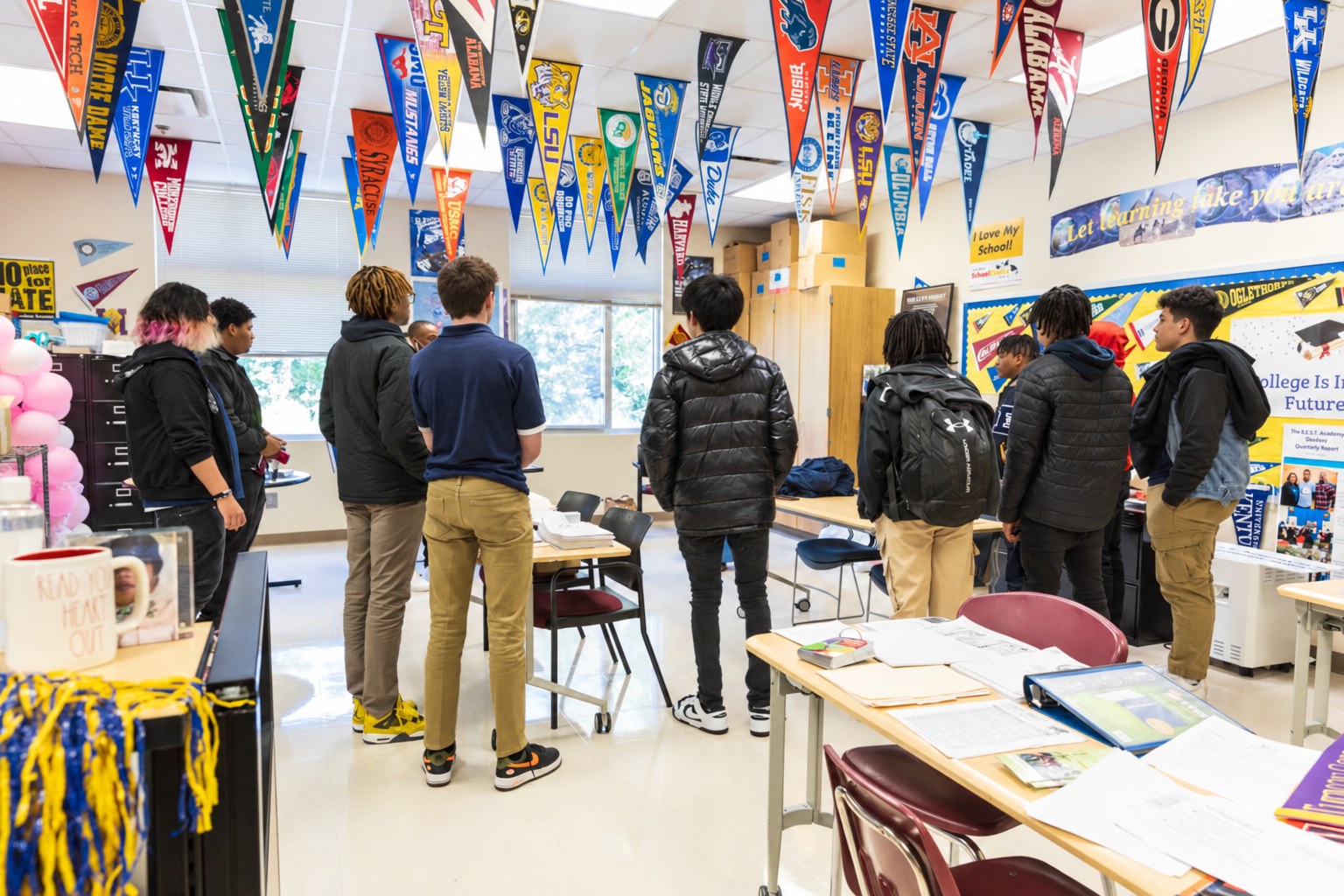 A middle school classroom hung with college pennants, students gathered for a lesson